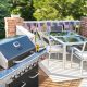 A view of an elevated patio with a dining room set, grill and American flag embordered railways.